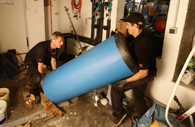 Abtransport: Der alte Warmwasserspeicher muss weichen Handwerker tragen den alten Speicher aus dem Keller.