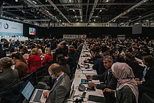 COP25 in Madrid: Delegierte an Tischen im Saal, links die Bühne