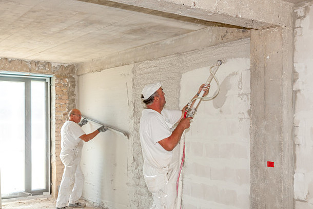 Zwei Männer bringen Dämmputz an die Wand.