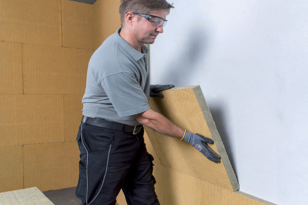 Mann klebt Dämmplatten an die Wand.