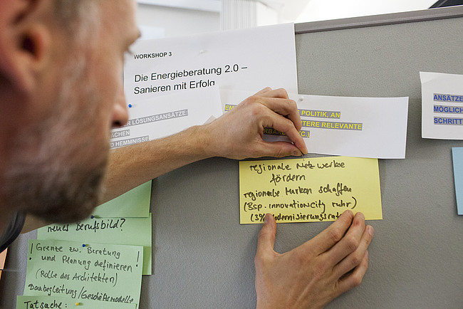 Mann pinnt Karte an Moderationsboard.