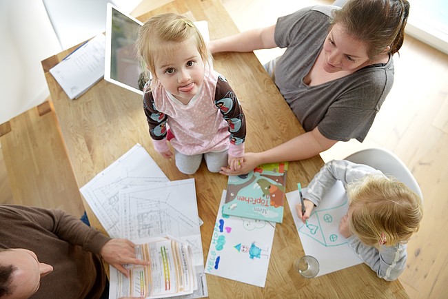 Familie Hopp am Tisch bei der Planung einer kontrollierten Wohnraumlüftung.