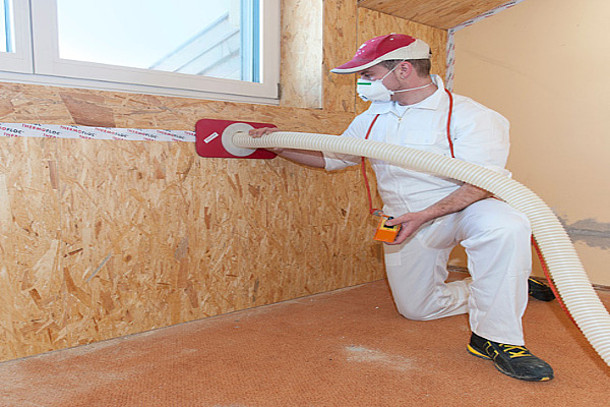 Mann bläst die Innendämmung ein.