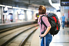 Frau wartet im Bahnhof auf einen Zug.