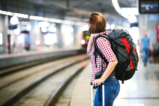 Frau wartet im Bahnhof auf einen Zug.