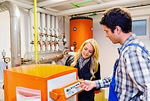 Handwerker und Eigentümerin stehen vor Brennwertkessel